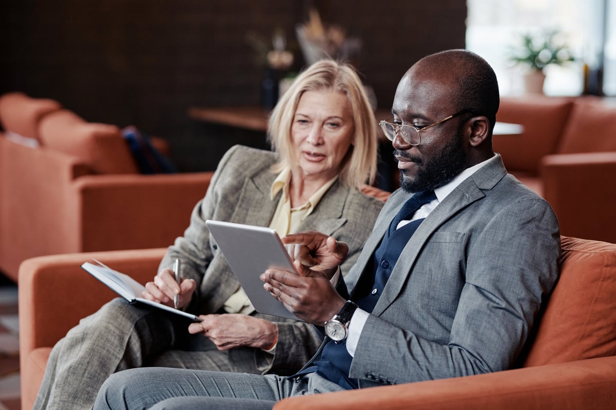 Empresario y empresaria revisando la planeación de su empresa en una mesa de trabajo